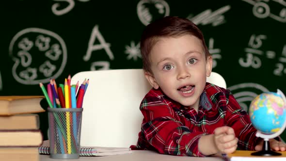 Cute child boy doing homework. Clever kid drawing at desk. Schoolboy. 