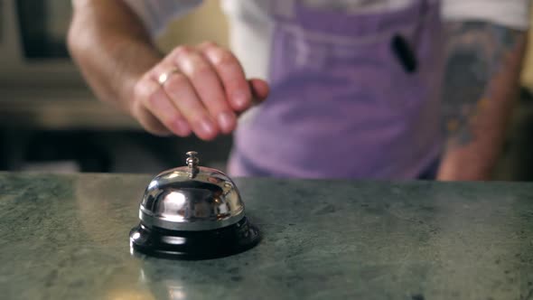 Close Up Macro Hand Chef and Ringing Bell Service on the Wooden in Kitchen Restaurant