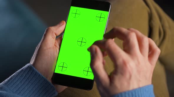 Man Using Smartphone with Green Mockup Screen in Vertical Mode