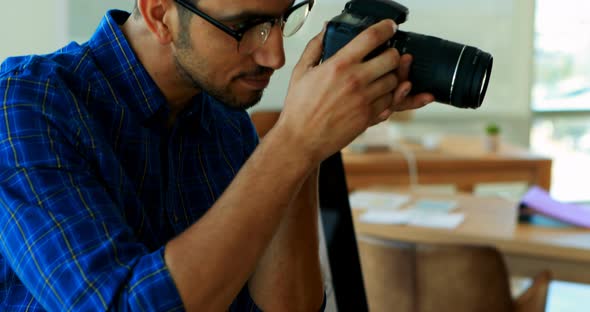 Male graphic designer using digital camera at his desk