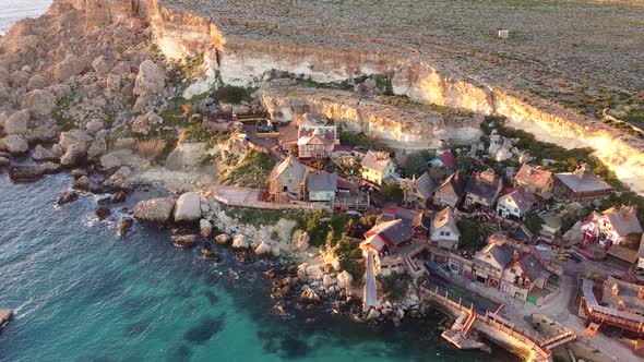 Wooden Popeye Village on rocky sea coastline, aerial view