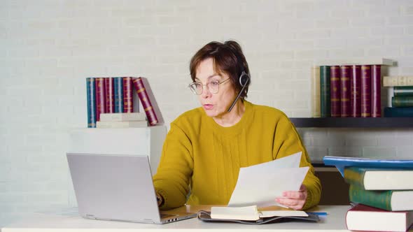 Slow Motion of a Senior Woman Works in Front of a Laptop Monitor in the Evening Office