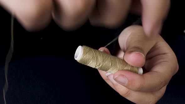 Winding light Brown sewing thread on spool with both hands