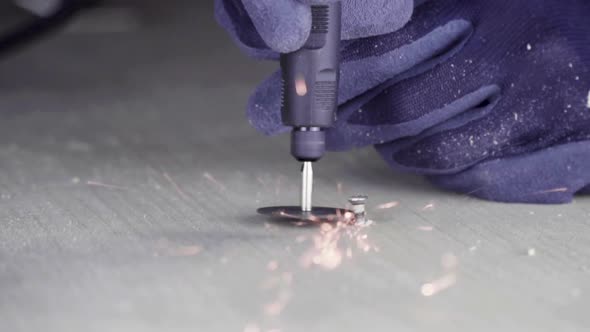 Woodworker using electric engraving tool to make carved decoration on piece of wood, close-up