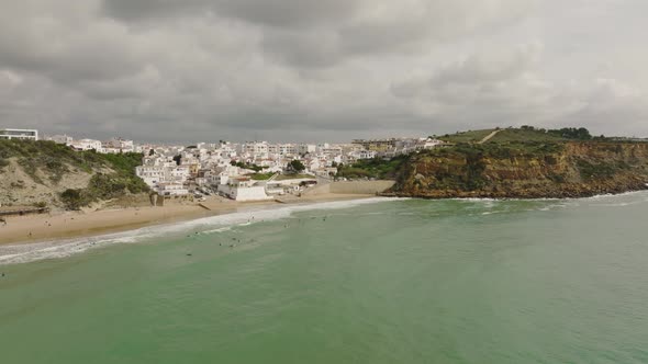 Aerial shot of surfers waiting for waves at a beach along the Atlantic Ocean in Portugal underneath