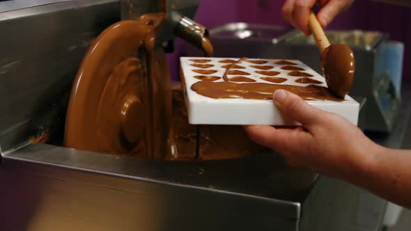 Worker filling mould with melted chocolate