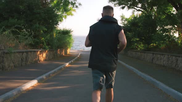 Back View of Handsome Active Middle Age Man with Long Gray Beard Running Outside By Sea