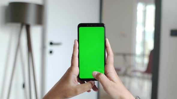 Handheld Camera Point of View of Young Woman at Cozy Apartment Using Phone With Green Mock Up Screen