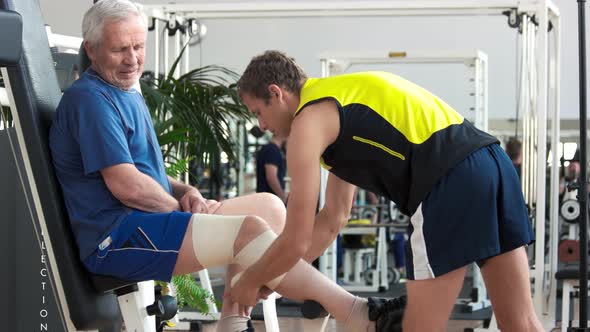 Man Wrapping with Bandage Leg of Elderly Man