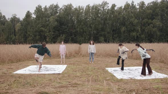 A Group of Young People Smeared with Black Paint are Dancing in Nature and Leaving the Drawing on