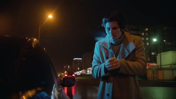 Young Stylish Man Lighting Up Cigarette Outdoors at Night