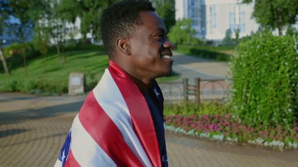 Side View Smiling Afroamerican Man Walking Street with American Flag on Back