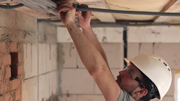 Male builder in the process of installing corrugated cable.