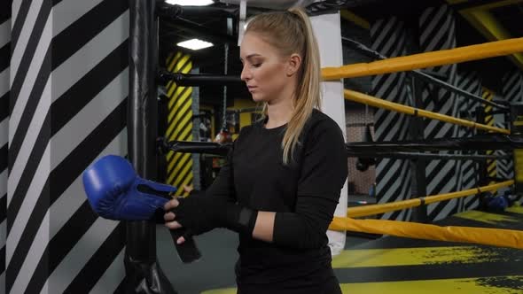 A Woman in Black Sportswear Puts on Boxing Gloves in a Boxing Gym