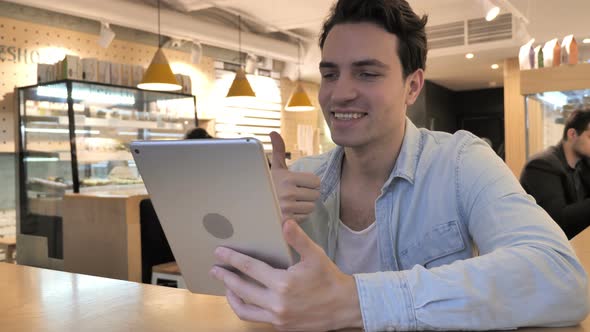 Video Chat on Tablet By Young Man in Cafe