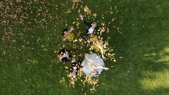 Aerial View Happy Wedding Couple Throws Leaves Up in a Beautiful Autumn Park