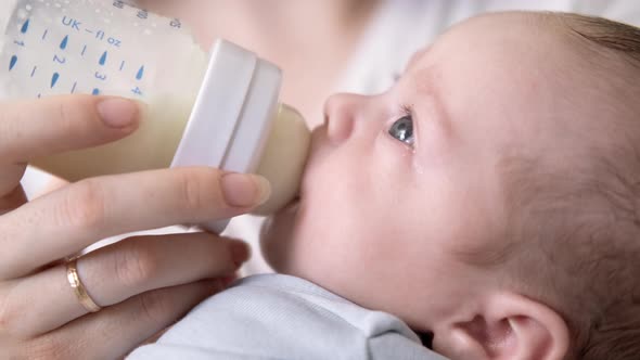 Loving Mother Feeding Her Little Boy Child with Milk Baby Bottle at Home Portrait Infant Baby Eating