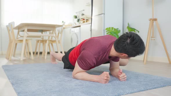 Asian handsome active young man doing cardio on floor in living room.