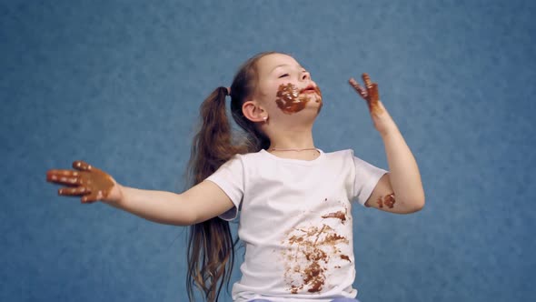 Cheerful little girl licking chocolate from her fingers