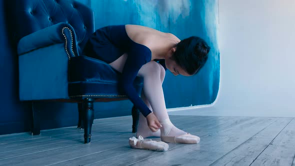 Attractive Girl Puts on White Ballet Pointe Shoes and Ties