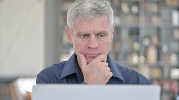 Portrait of Middle Aged Man Thinking and Working on Laptop