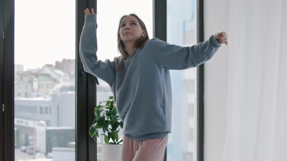 Young Woman in Blue Sweater Feeling the Music in Bright Apartment