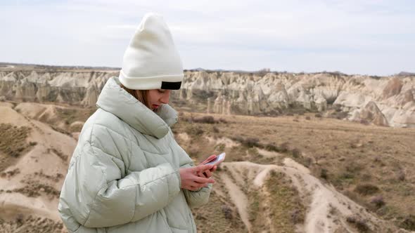 Girl Standing in Scenic Mountain Valley and Texting Via Cell Phone