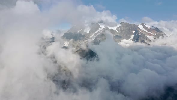 Epic Aerial Flight Through White Clouds Covering Snowy Mountain Summit in Winter