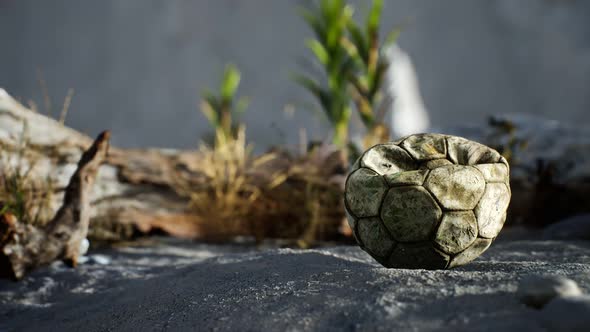 An Old Torn Soccer Ball Thrown Lies on Sand of Sea Beach alt