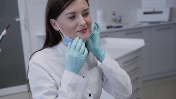 Pretty Dentist Wears Medical Mask Before Consulting Patient in Dental Clinic