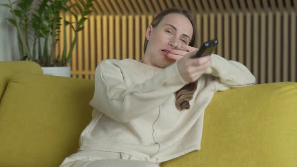 Woman Is Watching Films By Tv Screen in Her Home Switches Different Channels with a Remote Sitting