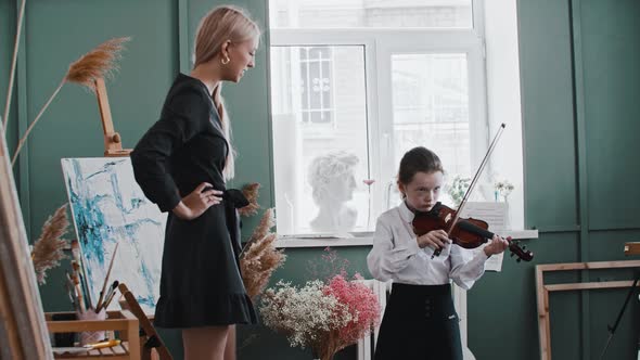 A Girl Playing Violin During Lesson with Blonde Woman Teacher