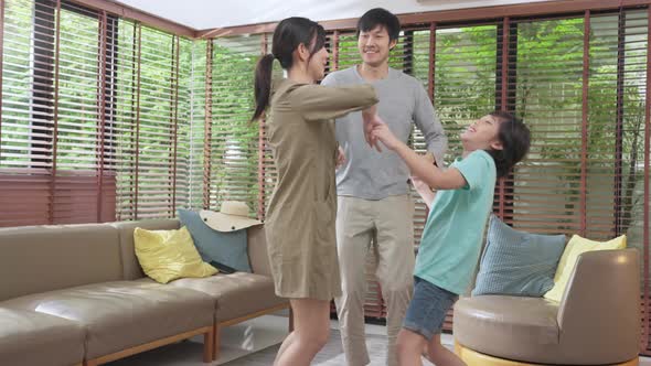 Happiness cheerful asian family dad mom and son funny dancing in living room