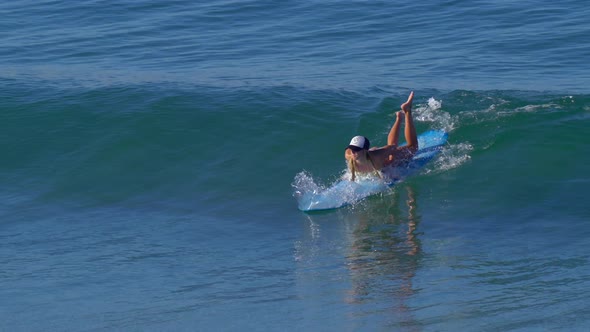 A young woman surfing in a bikini on a longboard surfboard.