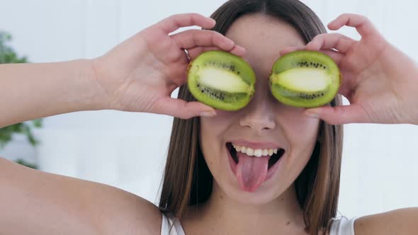 Attractive Happy Woman Posing with Kiwi on Eyes