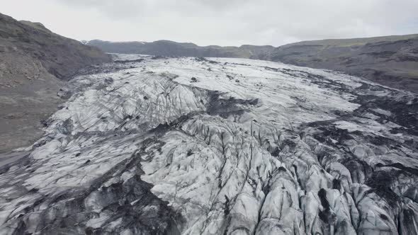 Aerial view over the Solheimajokull Glacier, in dark, cloudy Iceland - reverse, drone shot