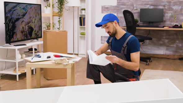 Young Male Worker Assembly Details of Furniture in New Home