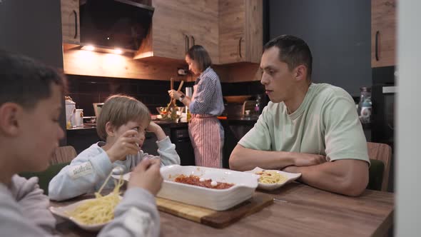 Young Happy Family Talking While Having Dinner at Home Table