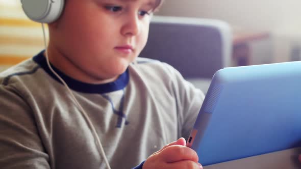 Boy in headphones using digital tablet in living room