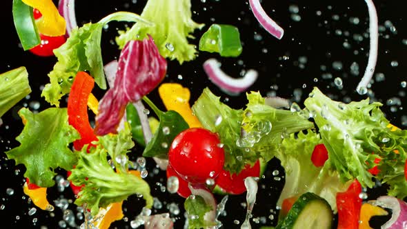 Super Slow Motion Shot of Flying Fresh Vegetables and Water Splash on Black Background at 1000Fps.