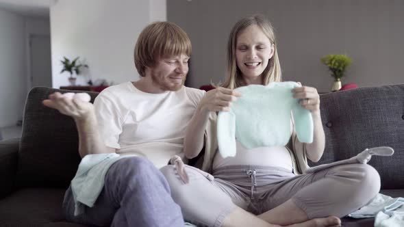 Happy Young Couple Looking at Clothes for Child