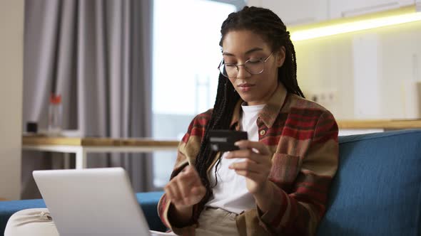 Young African American Holding Credit Card Using Laptop and Buying Online