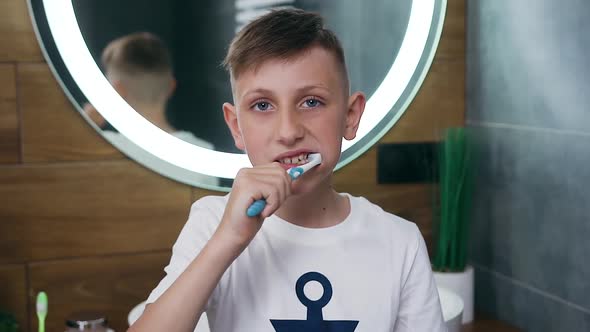 Boy Standing Near the Bathroom Mirror and Cleaning His Teeth while Posing on Camera