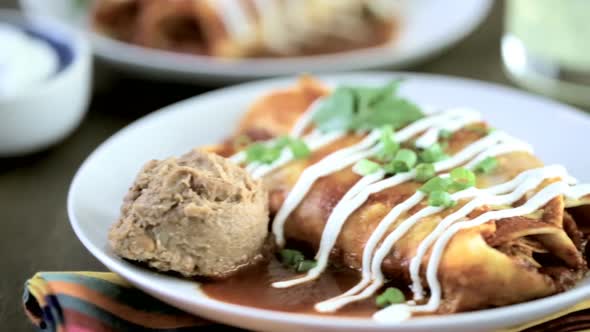 Close up of dinner plate with Chicken enchiladas garnished with green onions and sour cream.