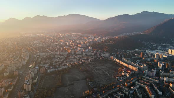 Aerial drone view of Brasov at sunrise, Romania. Roads, residential buildings, yellowed trees, Carpa