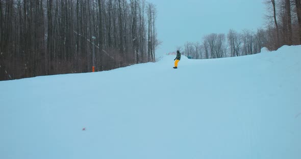 Athlete Snowboarder Rides on a Board on a Snowy Slope