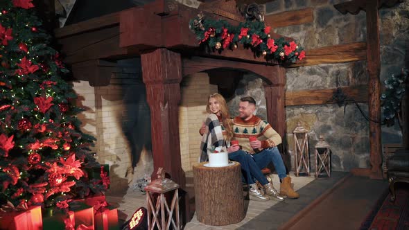 Christmas decorated fireplace in a house before holidays. Young couple warms near fireplace