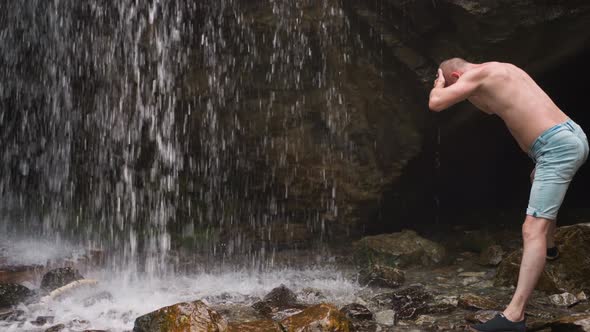 Man Hiker Catches Falling Down Water Drops Near Old Rock