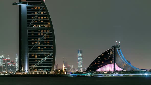Skyline of Dubai at Night Timelapse with Burj Al Arab in Foreground in Dubai United Arab Emirates