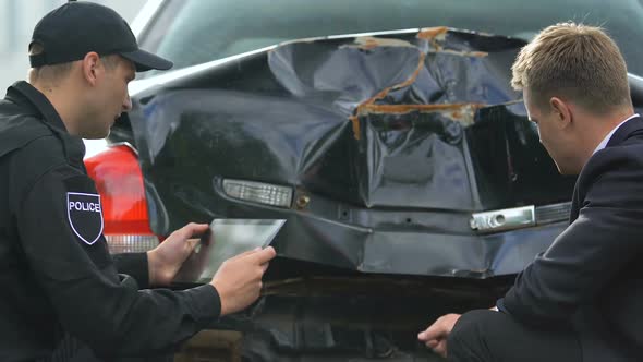 Male Officer Taking Tablet Photo of Damaged Car, Sad Driver Looking Smashed Auto